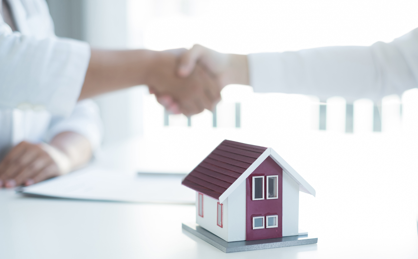 Businessmen and brokers real estate agents shake hands after completing negotiations to buy houses insurance and sign contracts. Home insurance concept.